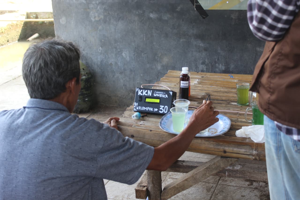 Adang Suparman mencoba Smart Water Monitoring(Sumber: KKN Unsika Kelompok 30)