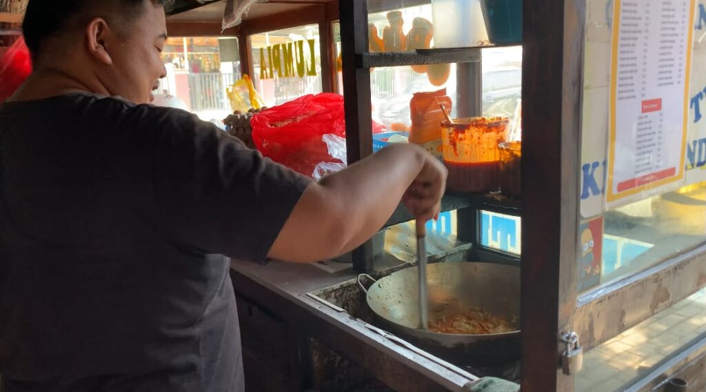 A Wendi sedang meracik pesanan seblak dan lumpia basah di kedainya yang berlokasi di depan kampus Unsika Karawang.(sumber: dokumen wartacana.com)